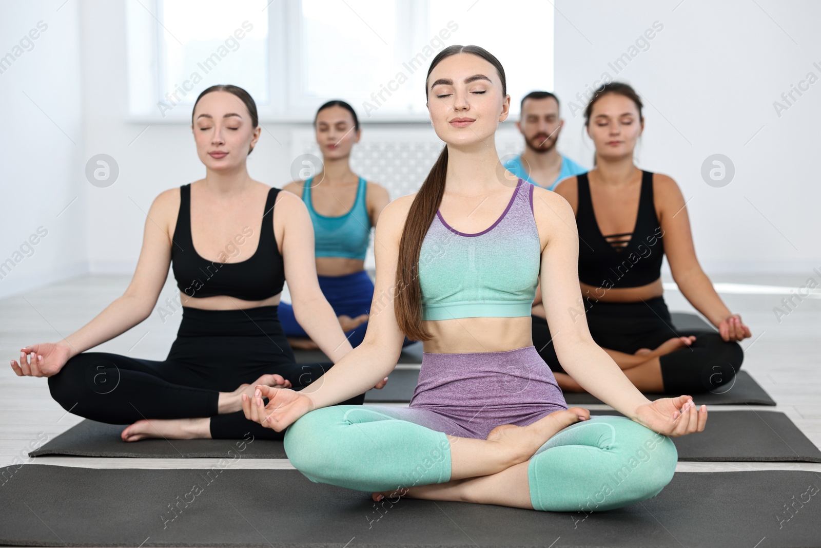 Photo of Group of people meditating on mats in yoga class