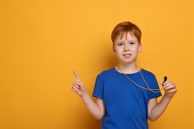 Photo of Little boy with whistle on orange background, space for text