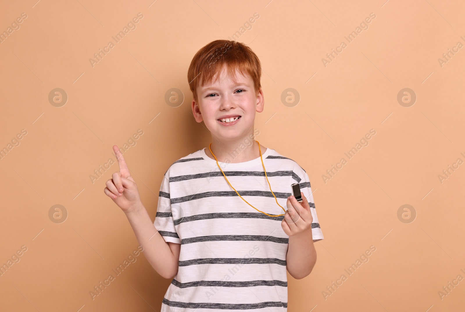 Photo of Little boy with whistle on beige background