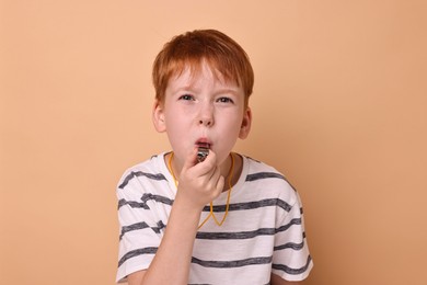 Little boy blowing whistle on beige background