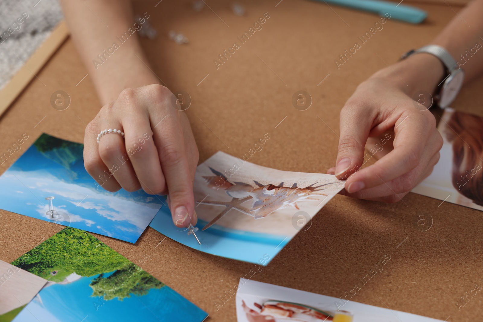 Photo of Creating vision board. Woman pinning photo to corkboard on floor indoors, closeup