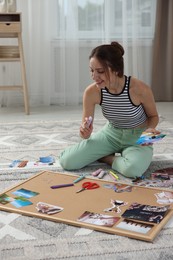 Photo of Woman creating vision board with different photos and other elements on floor indoors