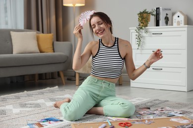 Woman creating vision board with different photos and other elements on floor indoors