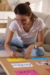 Creating vision board. Woman writing on card indoors