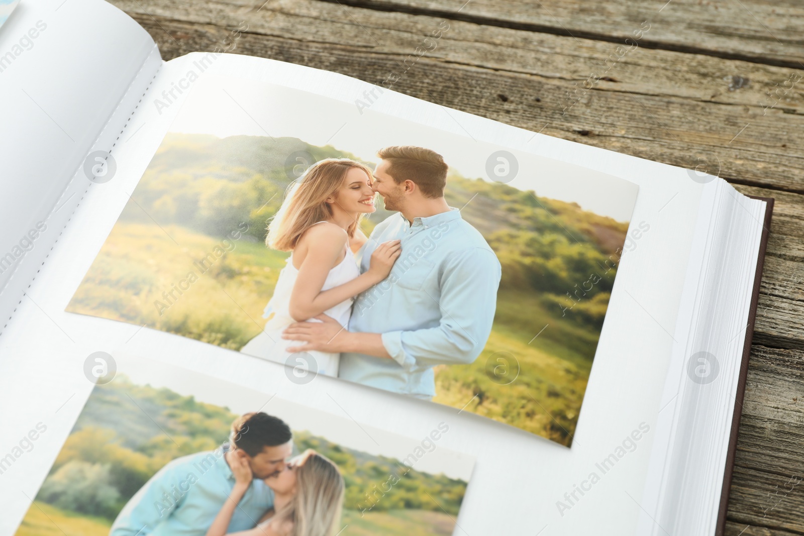 Photo of Different photos in open photo album on wooden table, closeup