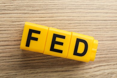 Photo of Cubes with letters Fed (Federal Reserve System) on wooden table, top view