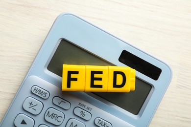 Photo of Cubes with letters Fed (Federal Reserve System) and calculator on white wooden table, top view