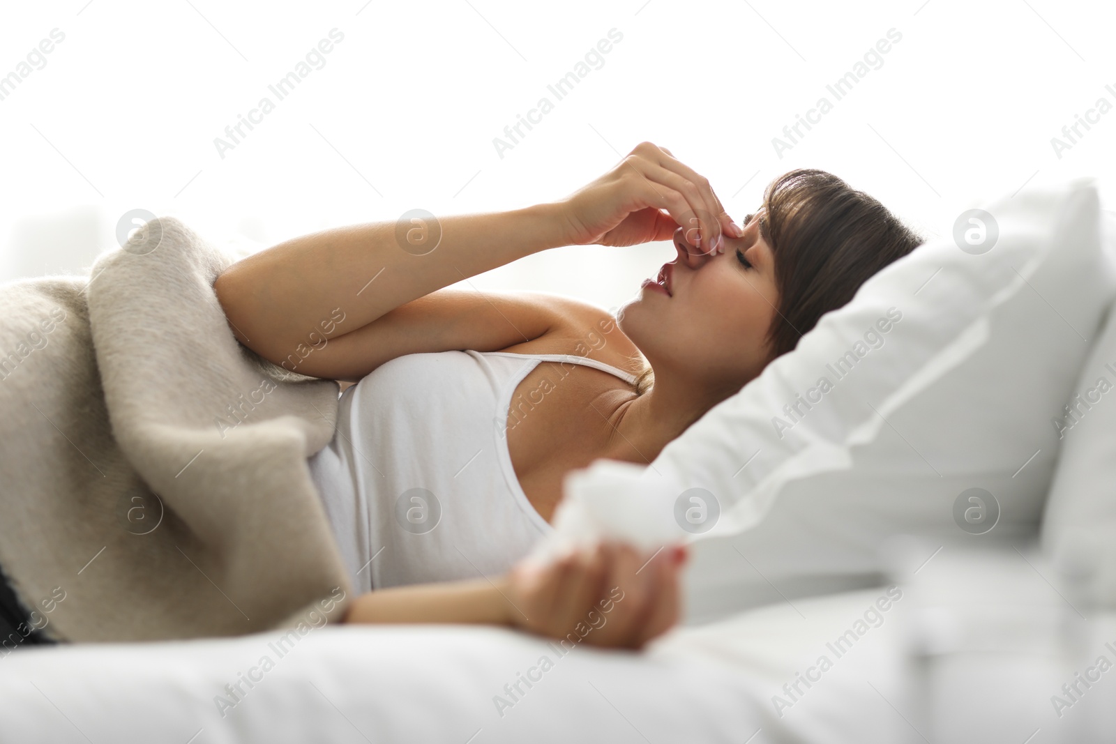 Photo of Woman with napkin suffering from sinusitis on bed