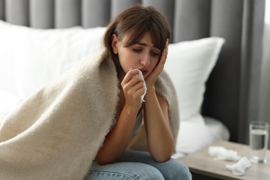 Woman wrapped in blanket suffering from sinusitis at home