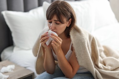 Woman wrapped in blanket suffering from sinusitis at home