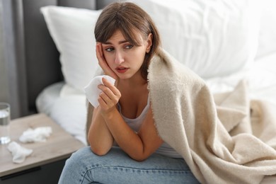 Woman wrapped in blanket suffering from sinusitis at home