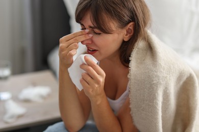 Woman wrapped in blanket suffering from sinusitis at home