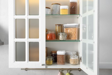 Photo of Different types of cereals and legumes in containers in kitchen