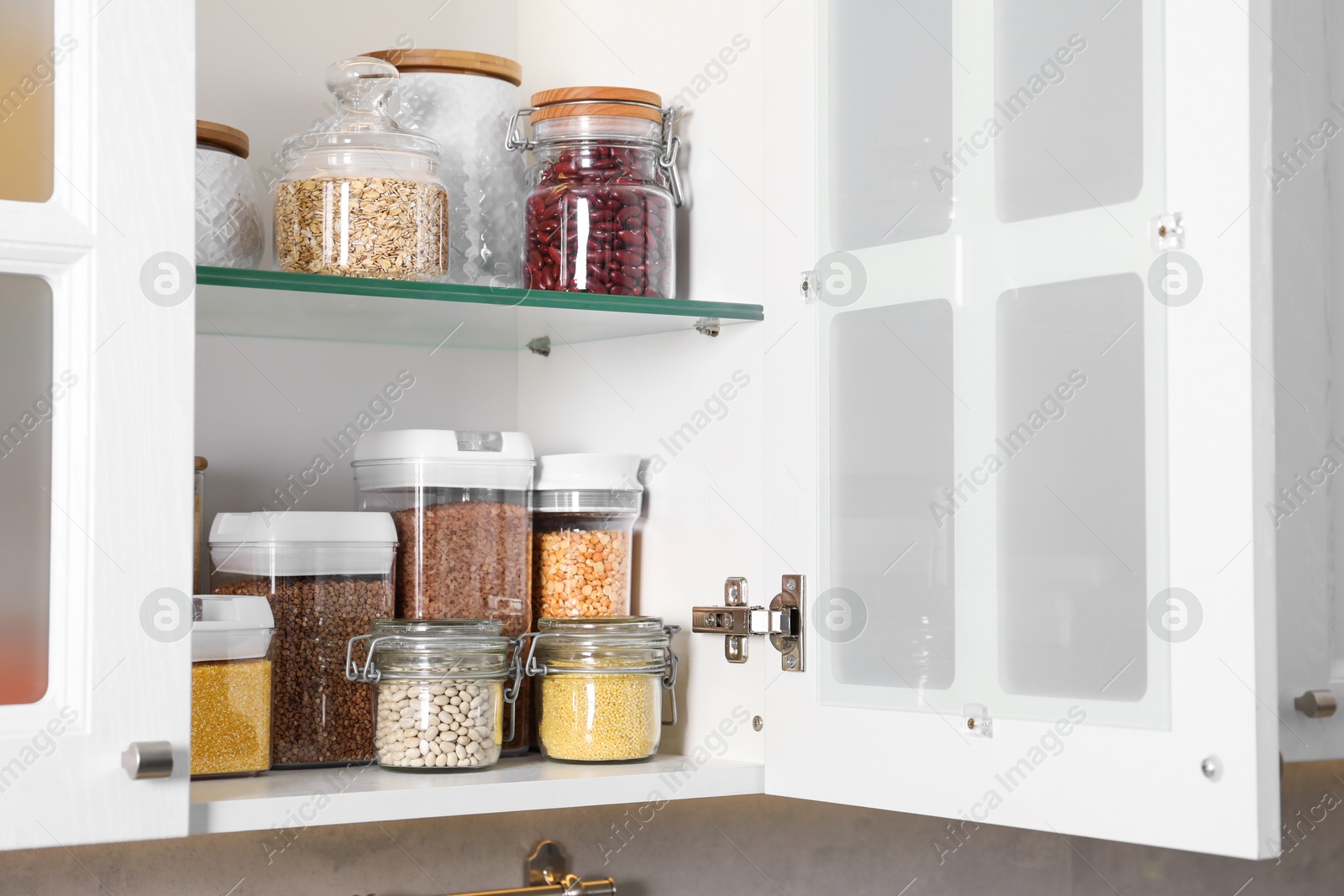 Photo of Different types of cereals and legumes in containers in kitchen