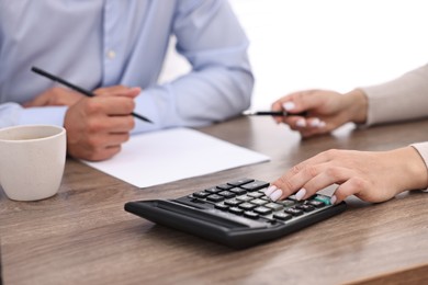 Photo of Banker working with client at wooden table in office, closeup