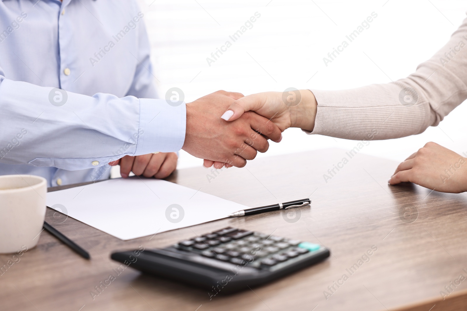 Photo of Banker and client shaking hands at table in office, closeup