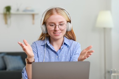 Interpreter in headphones having video chat via laptop indoors