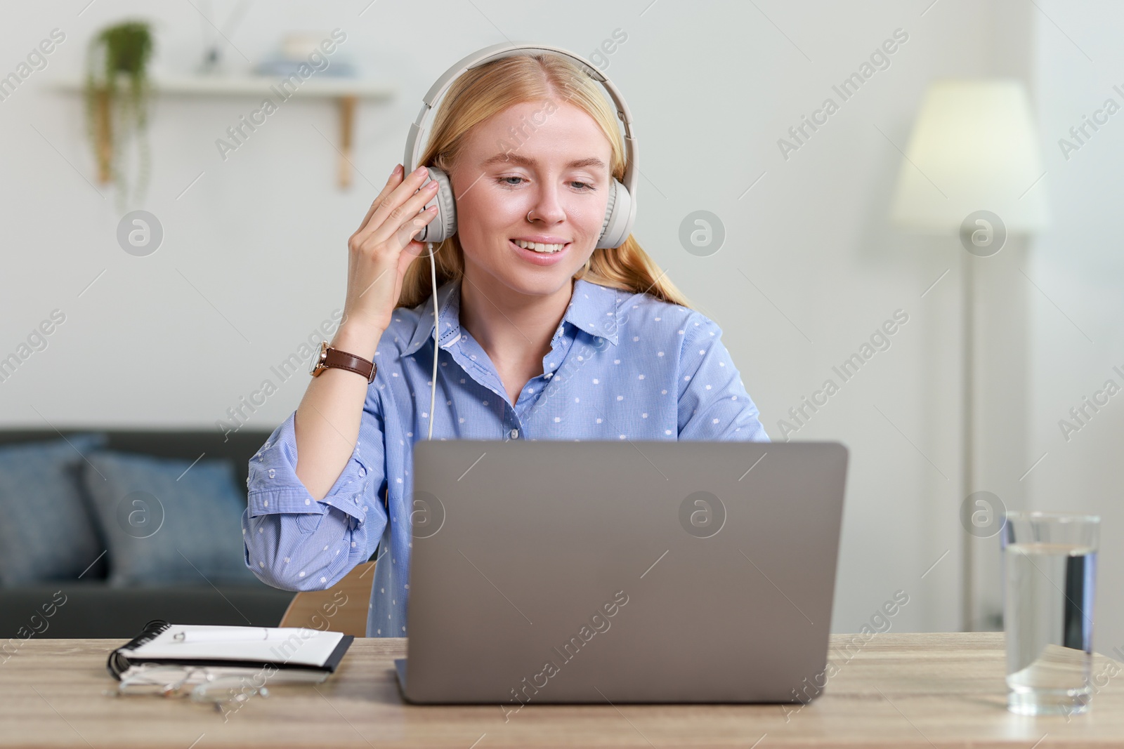 Photo of Interpreter in headphones working with laptop at table indoors