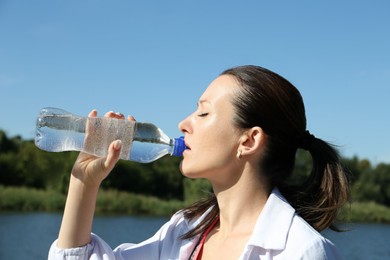 Photo of Woman drinking tasty soda water outdoors on sunny day