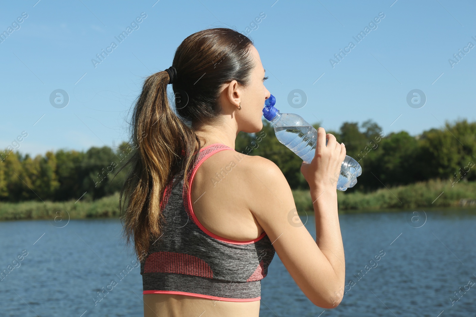 Photo of Woman drinking tasty soda water outdoors, back view