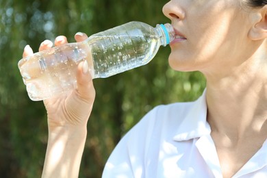 Photo of Woman drinking tasty soda water outdoors, closeup