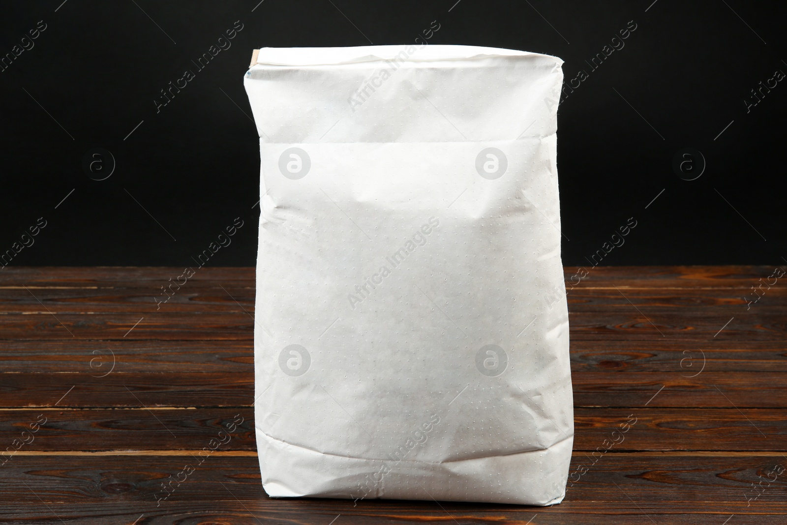 Photo of Bag of cement powder on wooden table. Building material