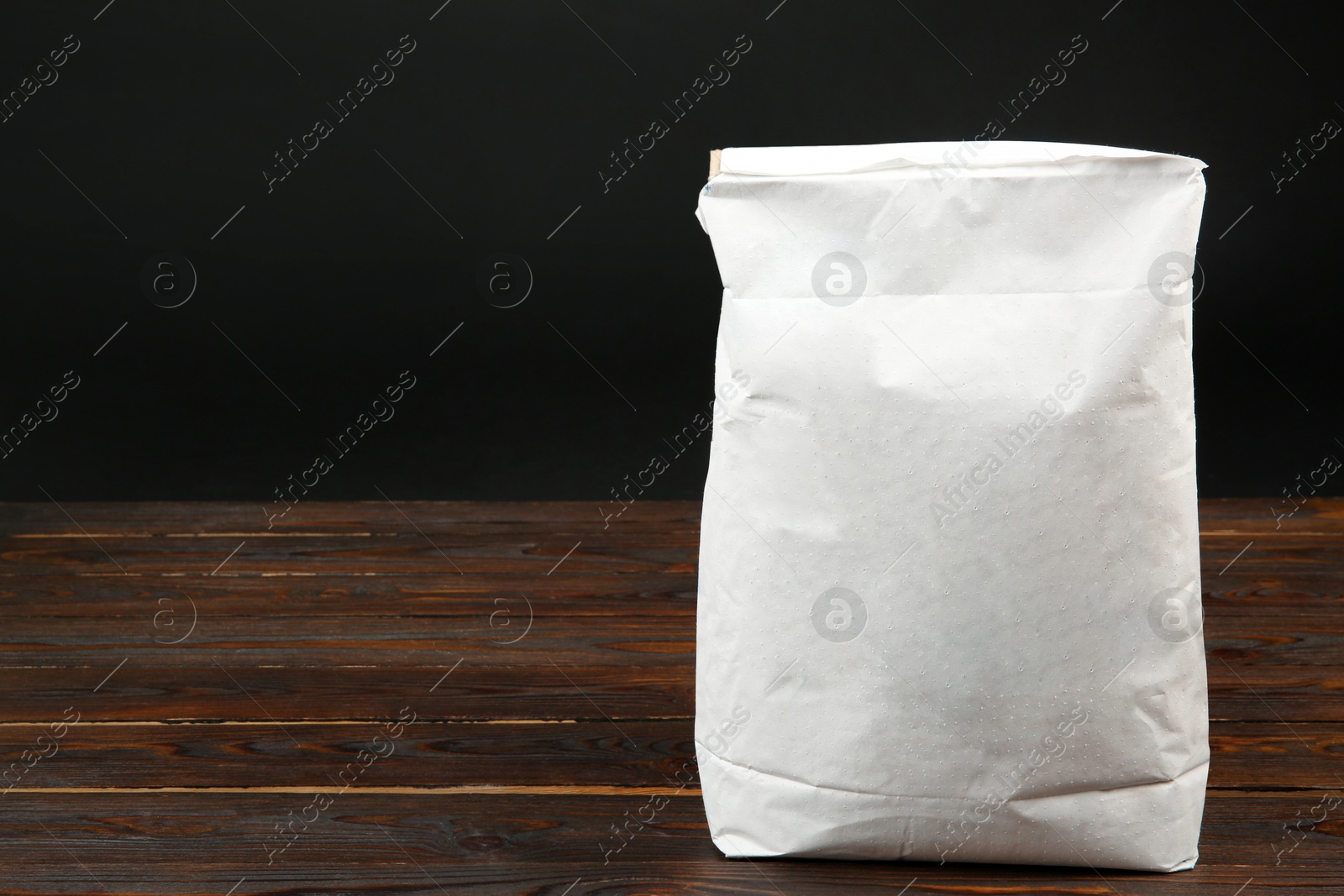 Photo of Bag of cement powder on wooden table, space for text. Building material