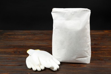 Bag of cement powder and rubber gloves on wooden table. Building material