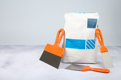 Bag of cement and trowels on textured table against light background. Space for text