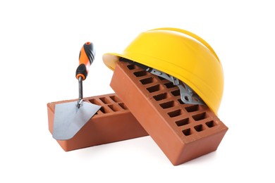 Photo of Red bricks, hard hat and trowel on white background