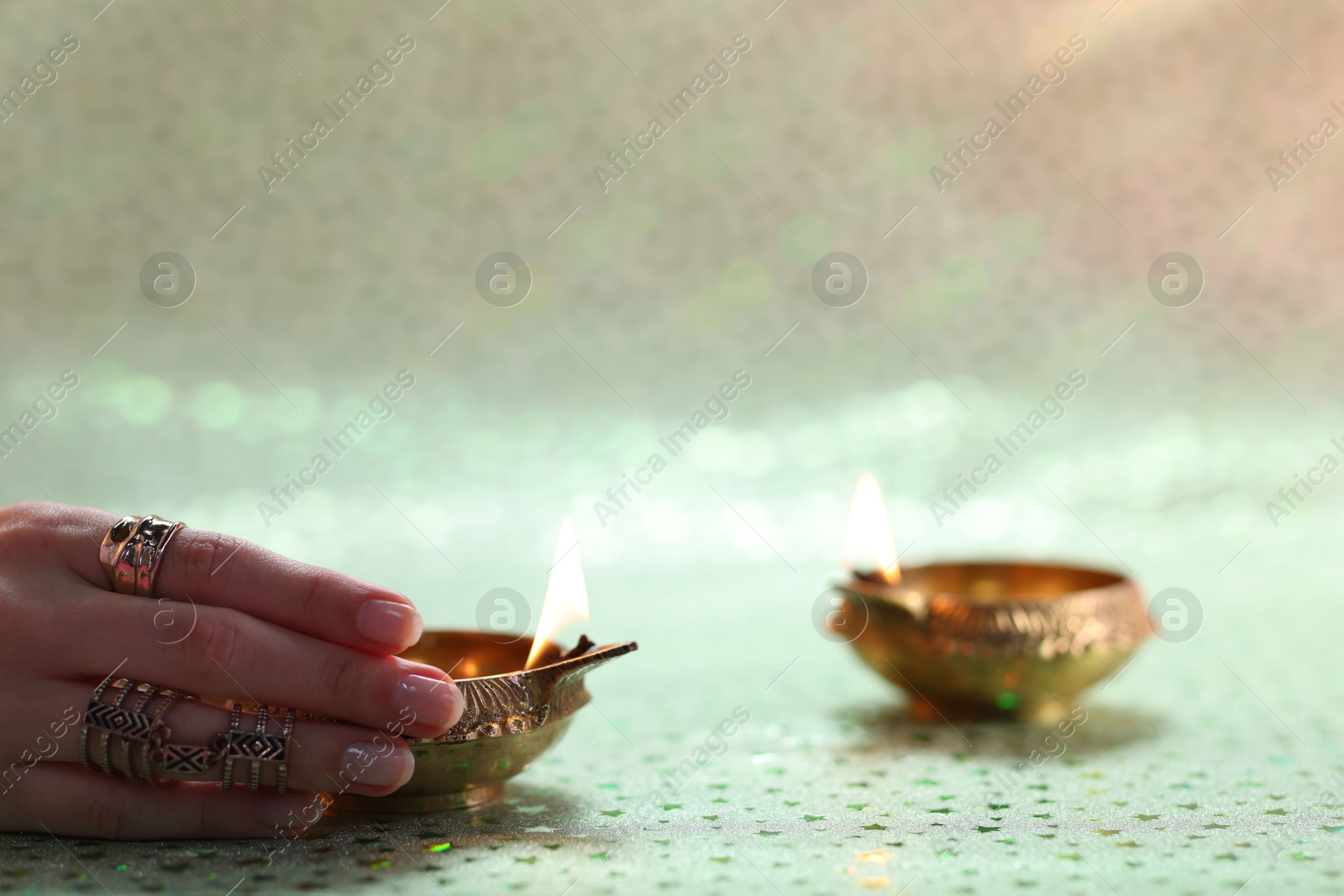 Photo of Diwali celebration. Woman with lit diya lamp on color background, closeup