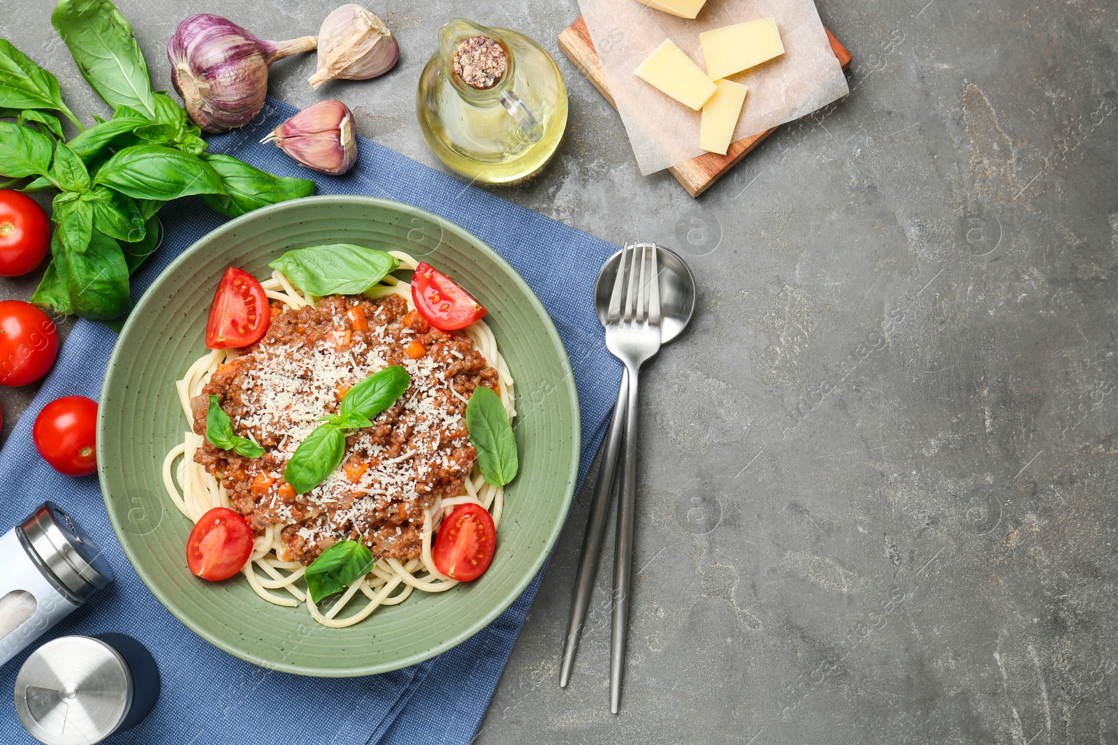 Photo of Delicious pasta bolognese with basil and tomatoes served on grey table, flat lay. Space for text