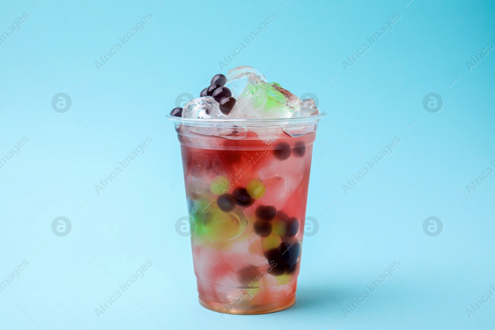 Photo of Tasty bubble tea in plastic cup on light blue background