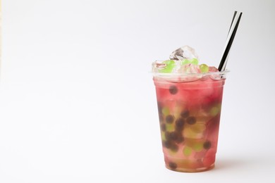 Photo of Tasty bubble tea in plastic cup on white background, space for text