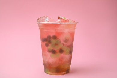 Photo of Tasty bubble tea in plastic cup on pink background