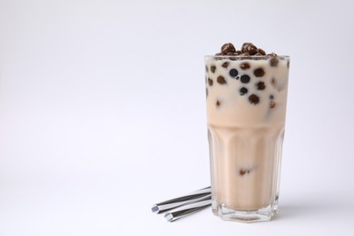 Photo of Tasty milk bubble tea in glass and straws on white background, space for text