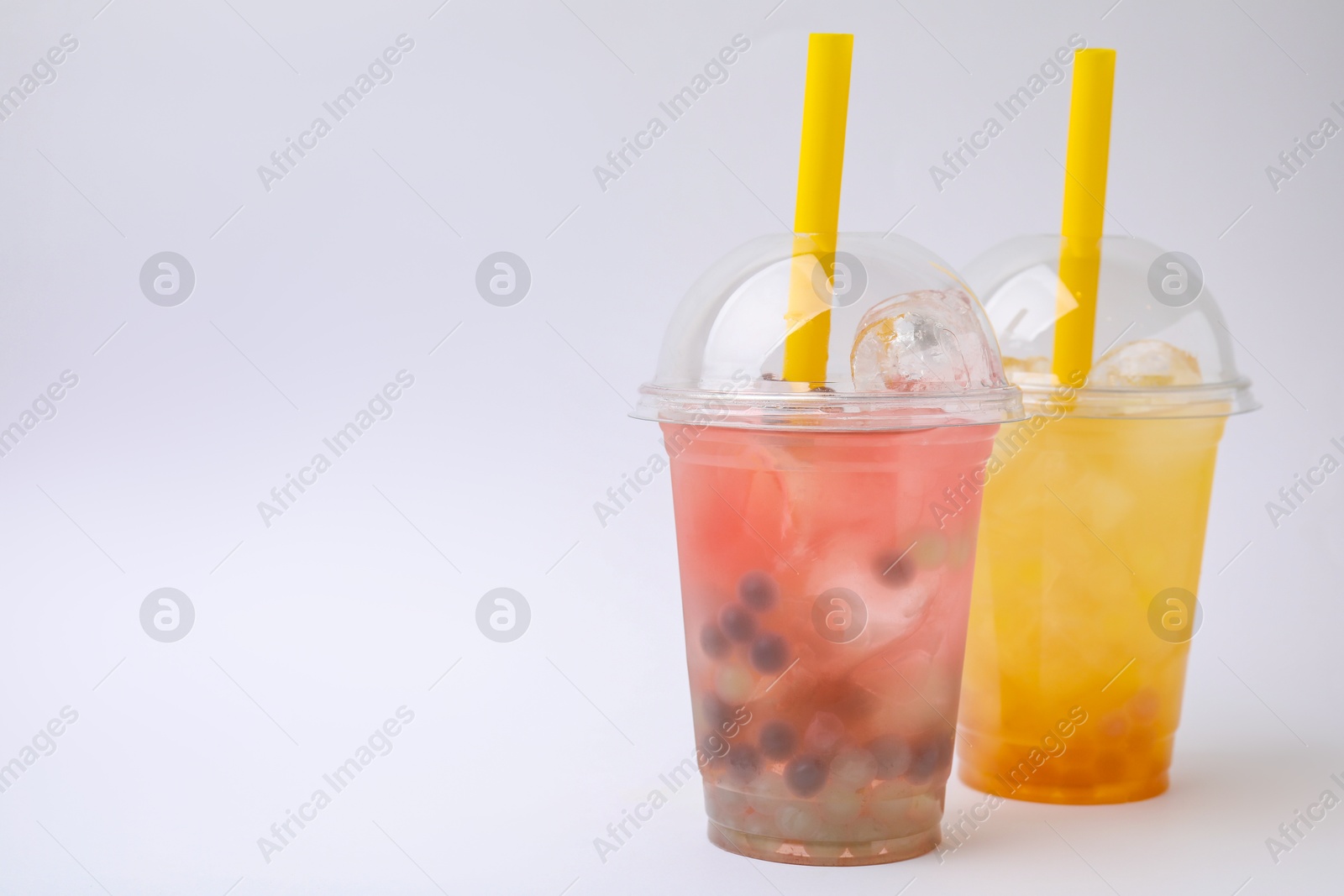 Photo of Tasty bubble tea in plastic cups on white background