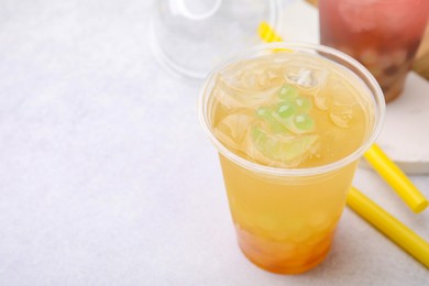 Photo of Tasty bubble tea in plastic cups and straws on light table, closeup. Space for text