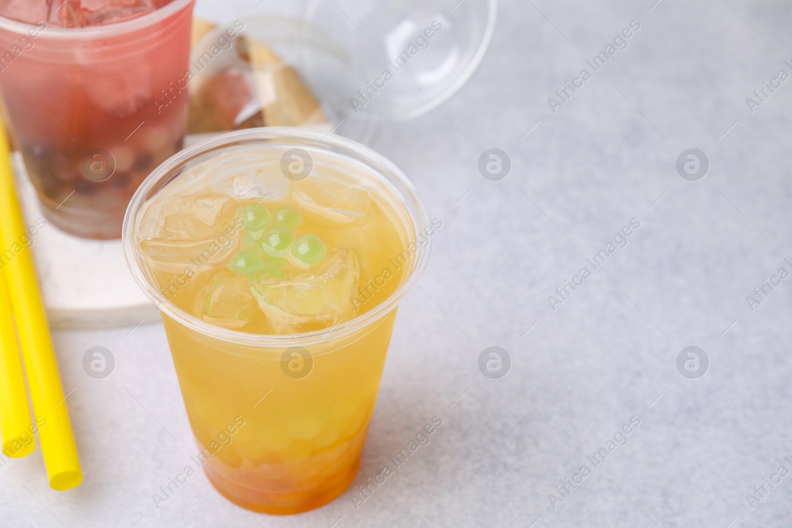 Photo of Tasty bubble tea in plastic cups and straws on light table, closeup. Space for text