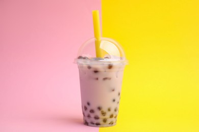 Photo of Tasty milk bubble tea in plastic cup on color background