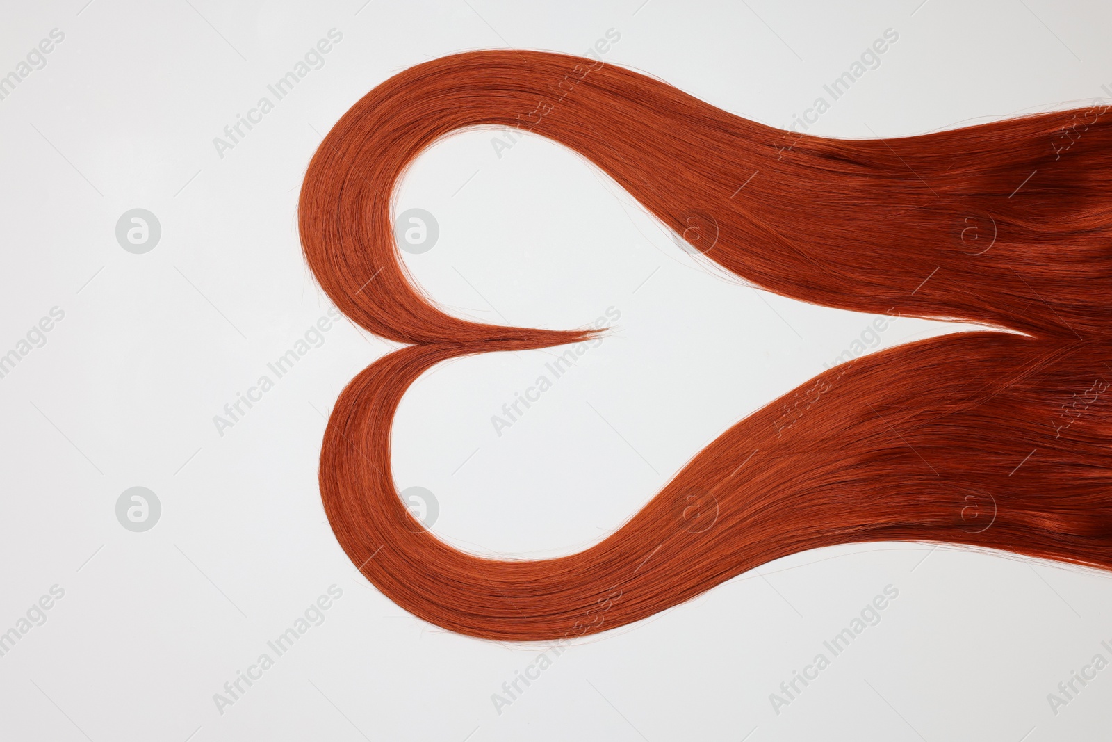 Photo of Red hair strands in shape of heart on white background, top view. Space for text