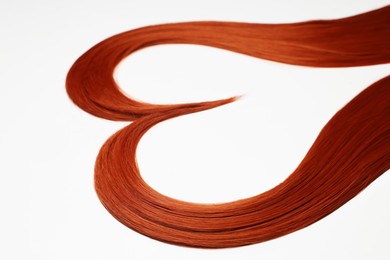 Photo of Red hair strands in shape of heart on white background, closeup