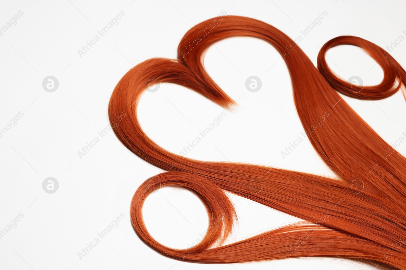 Photo of Red hair strands in shape of heart on white background, closeup