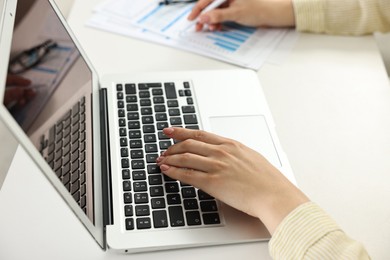 Budget planning. Woman using laptop at white table, closeup