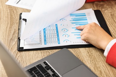 Budget planning. Woman with papers at wooden table, closeup