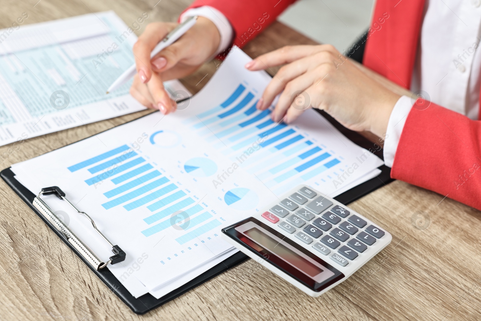 Photo of Budget planning. Woman with papers and calculator at wooden table, closeup