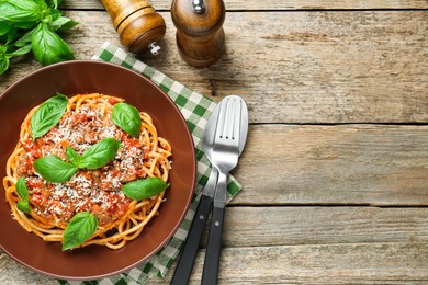 Photo of Delicious pasta bolognese with basil served on wooden table, top view. Space for text