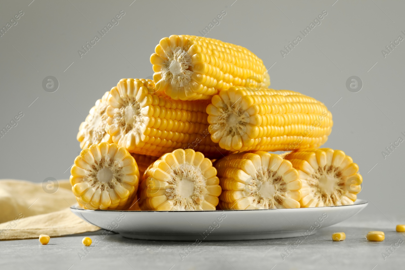 Photo of Halves of fresh ripe corncobs on grey table