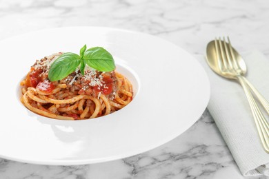 Photo of Delicious pasta bolognese with basil on white marble table, closeup