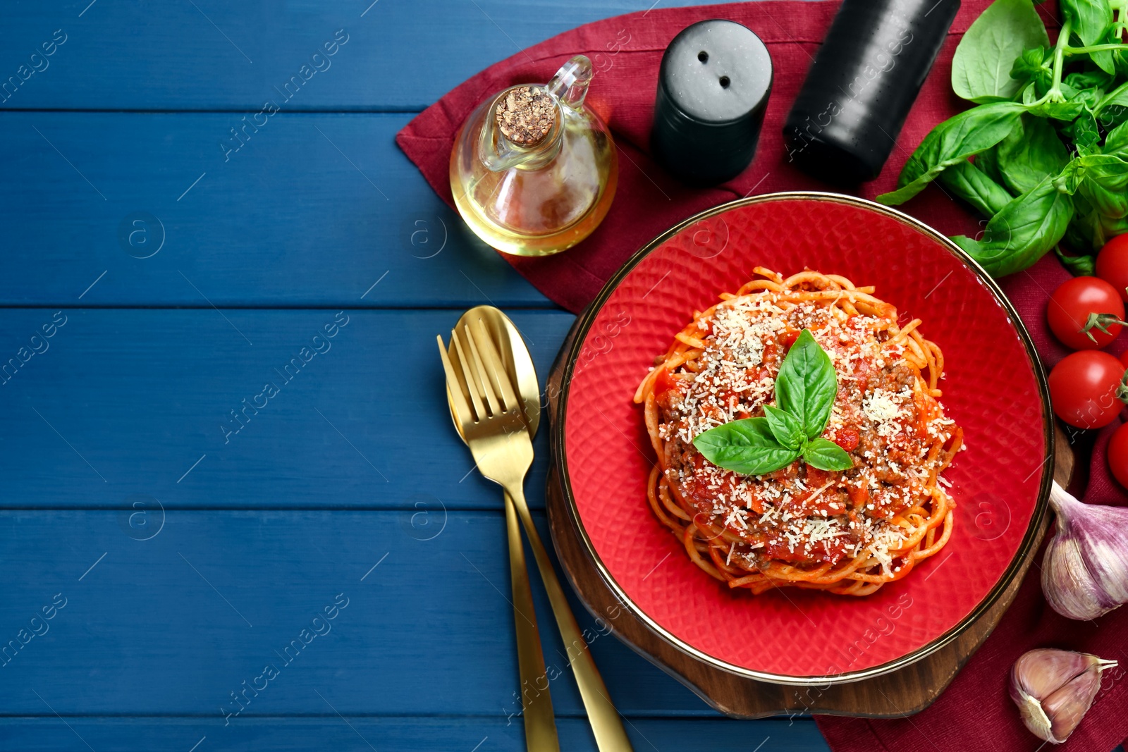 Photo of Delicious pasta bolognese with basil served on blue wooden table, top view. Space for text